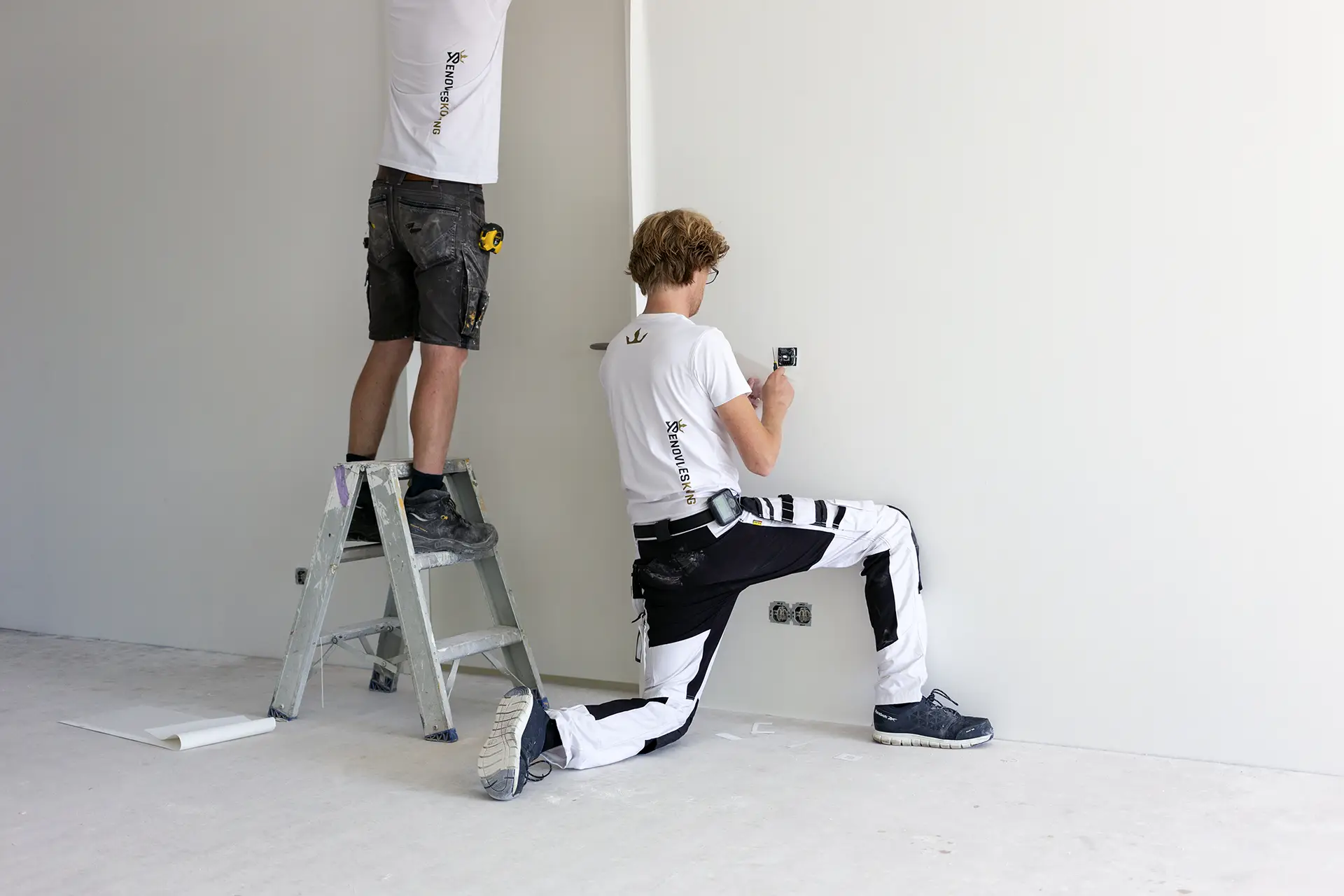 Vakmannen in Nijkerk die met precisie werken aan de afwerking van renovlies behang