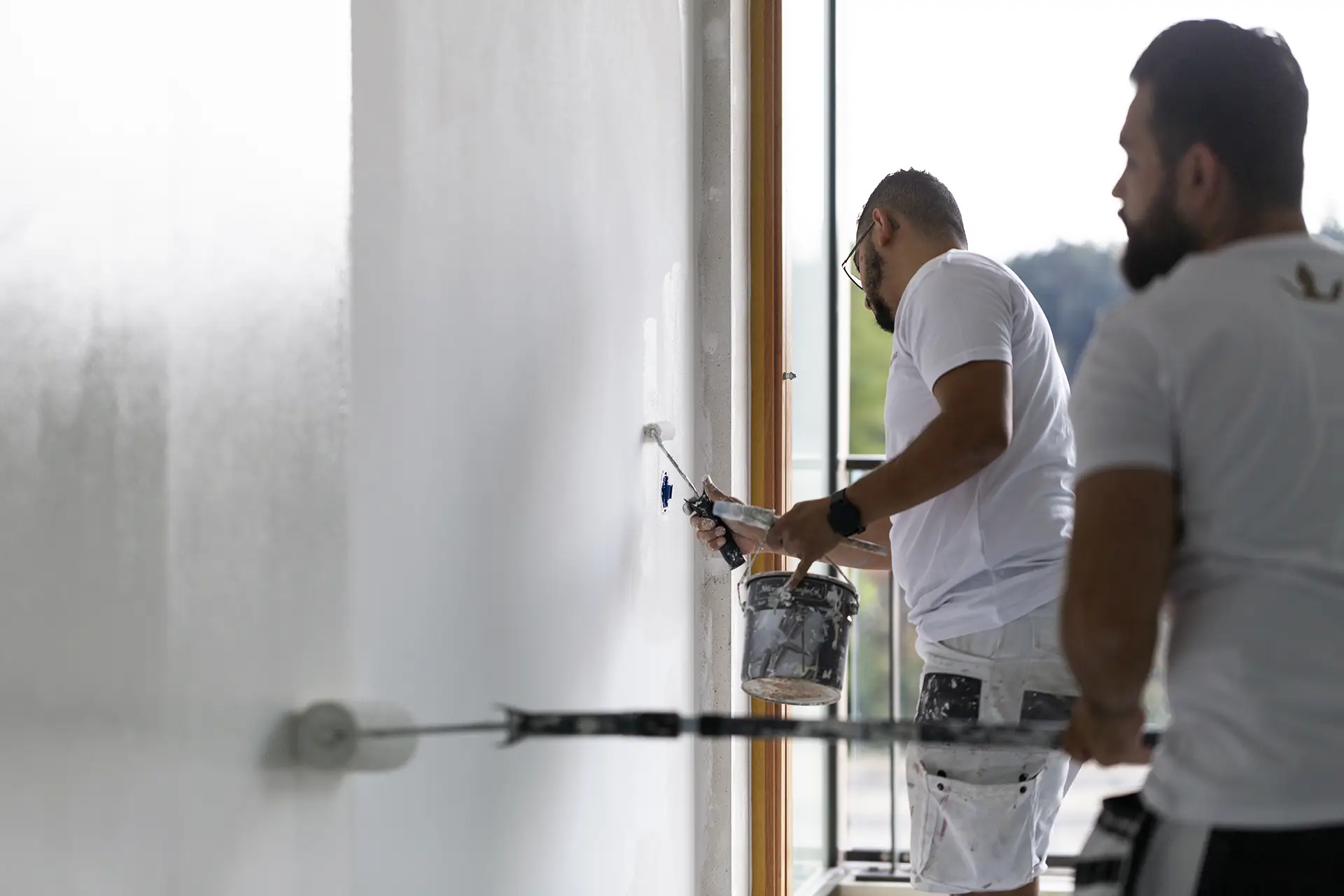 Een ervaren renovlies behanger uit Nijkerk is bezig met het sauzen van renovlies op een muur.
