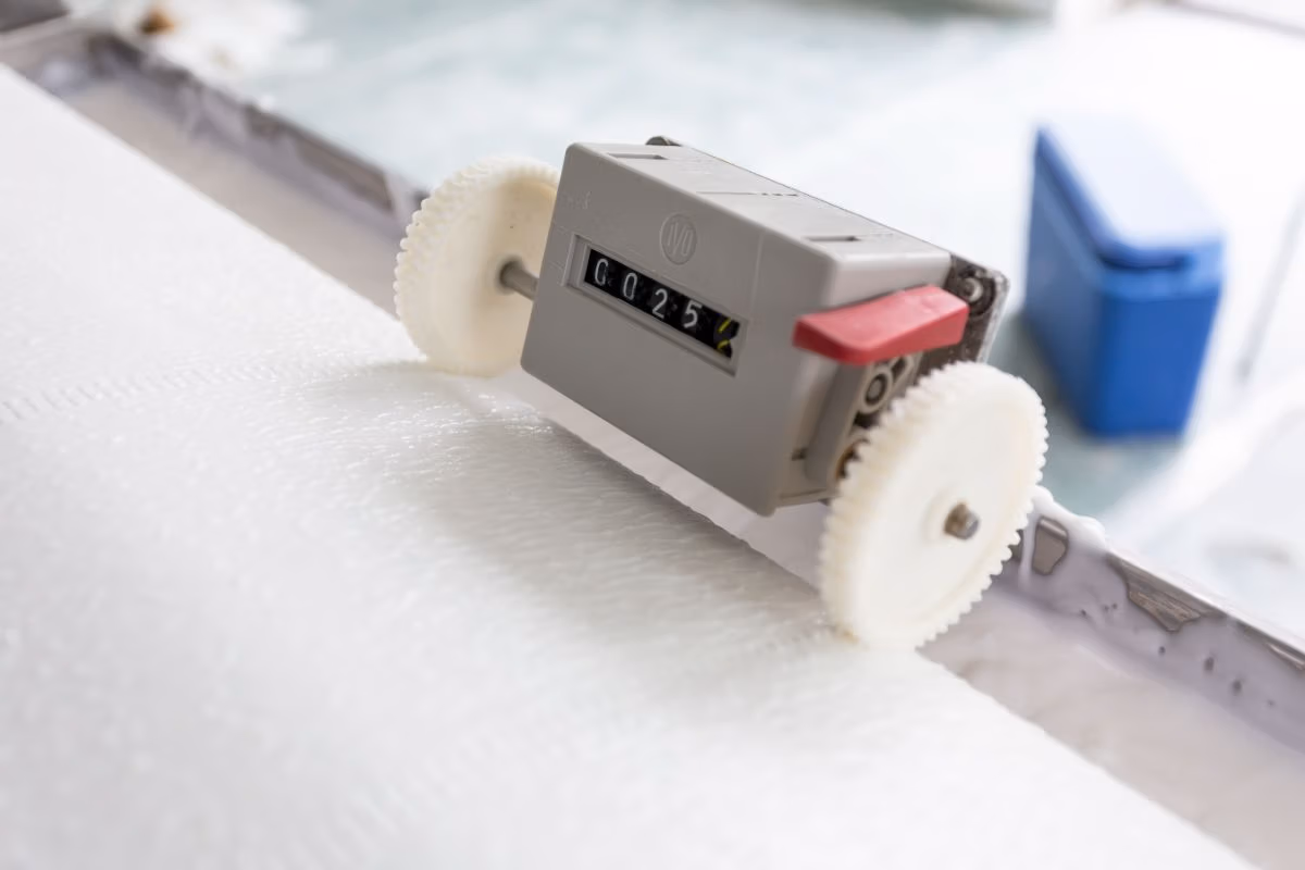 Een glasvlies behanger snijdt nauwkeurig behangpapier met een snijmachine op een werkbank voor een perfecte afwerking